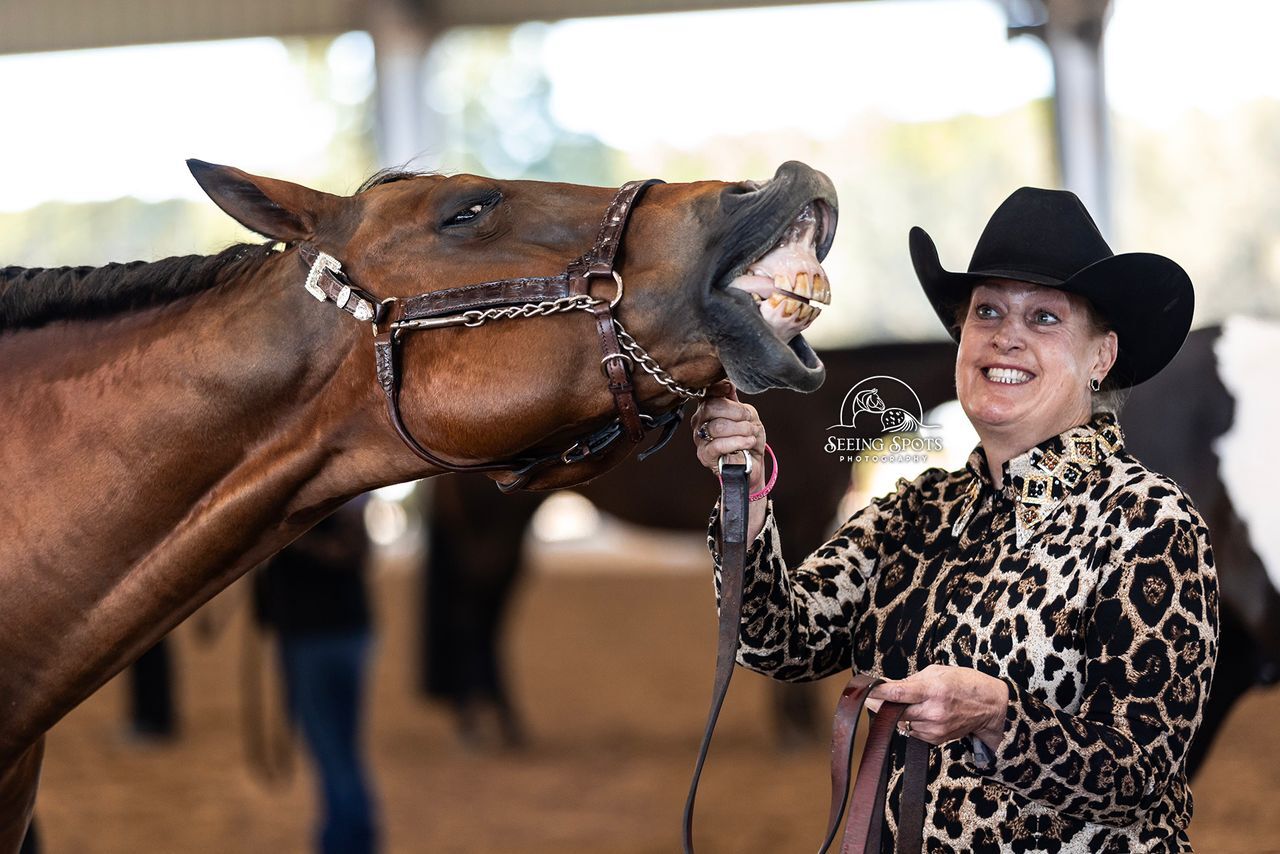 A smiling exhibitor sharing a playful moment with a horse